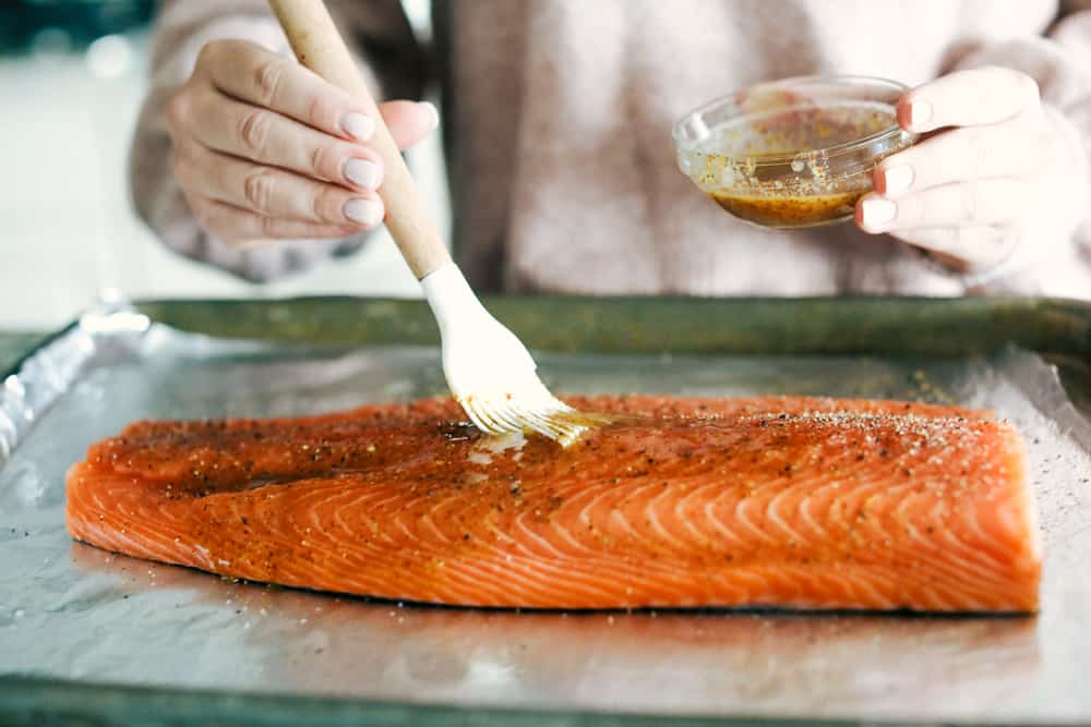 A salmon being basted with the marinated sauce. 