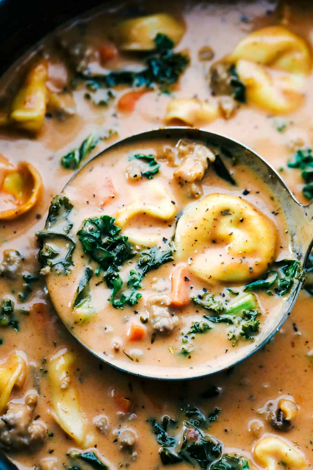 Closeup of tortellini soup in a ladle.