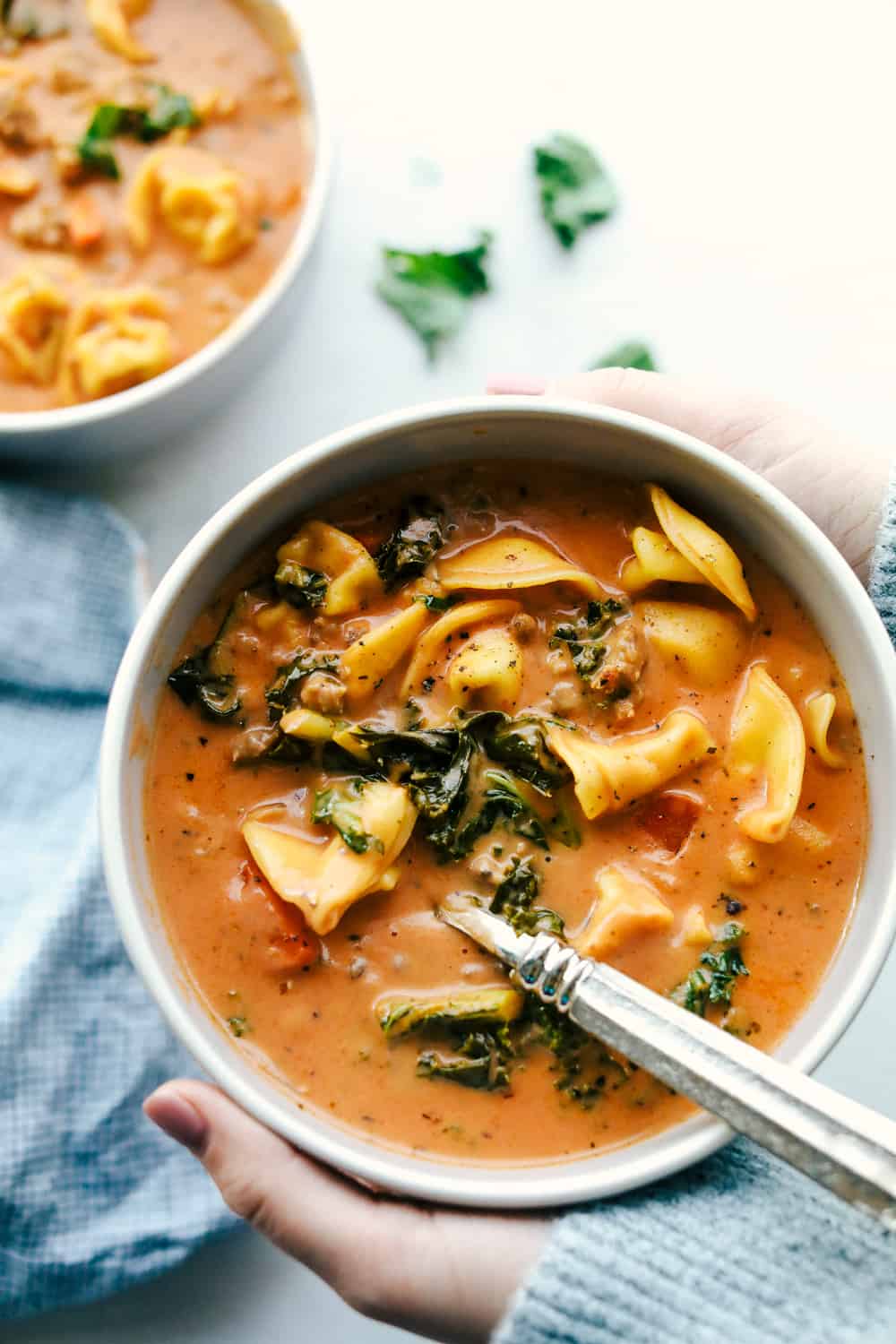 Creamy sausage tortellini soup served in a white bowl.