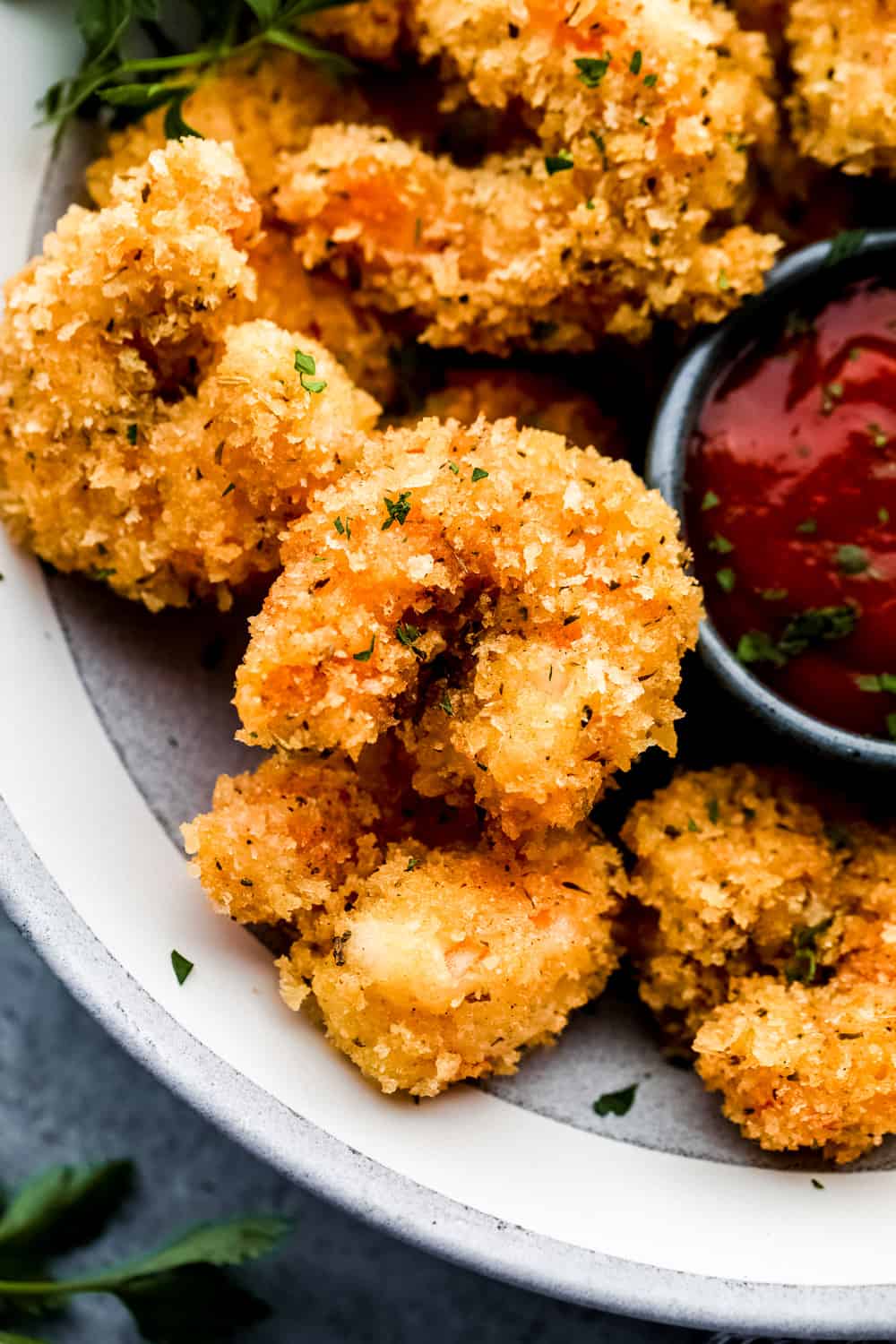 Cajun popcorn shrimp up close on a plate with cocktail sauce. 