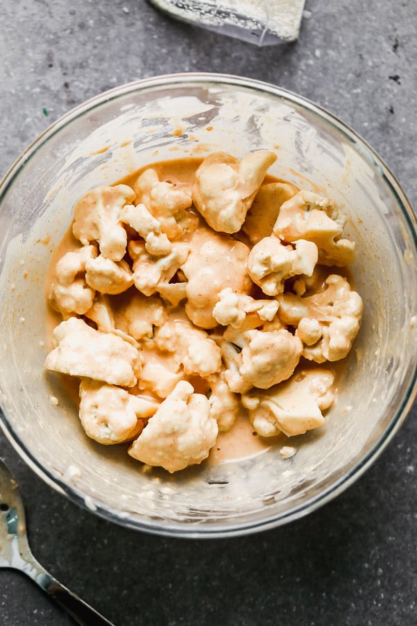 Cauliflower mixed in buffalo sauce in a bowl.