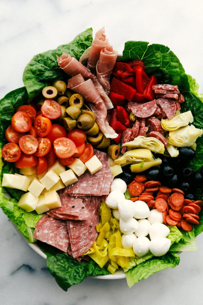 Antipasto salad with the ingredients spread out over the salad into sections. 