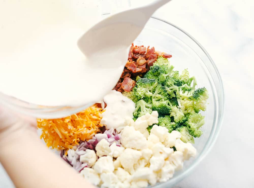 All the ingredients chopped up with the mayonnaise dressing being poured overtop. 