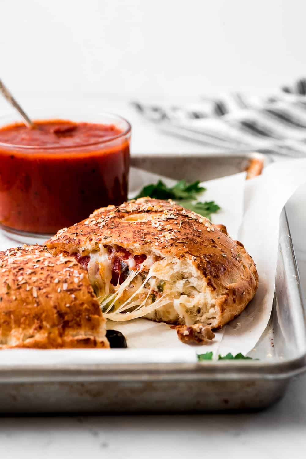 A calzone cut in half with melted cheese stringing between the halves.