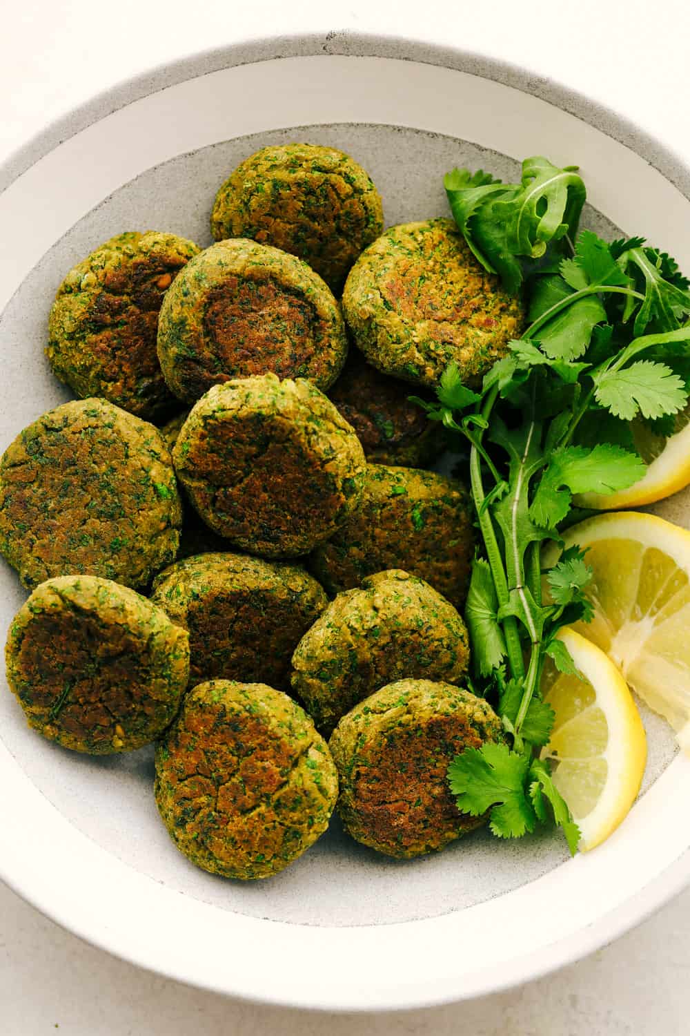 Falafel on a plate with lemon as a garnish and cilantro. 