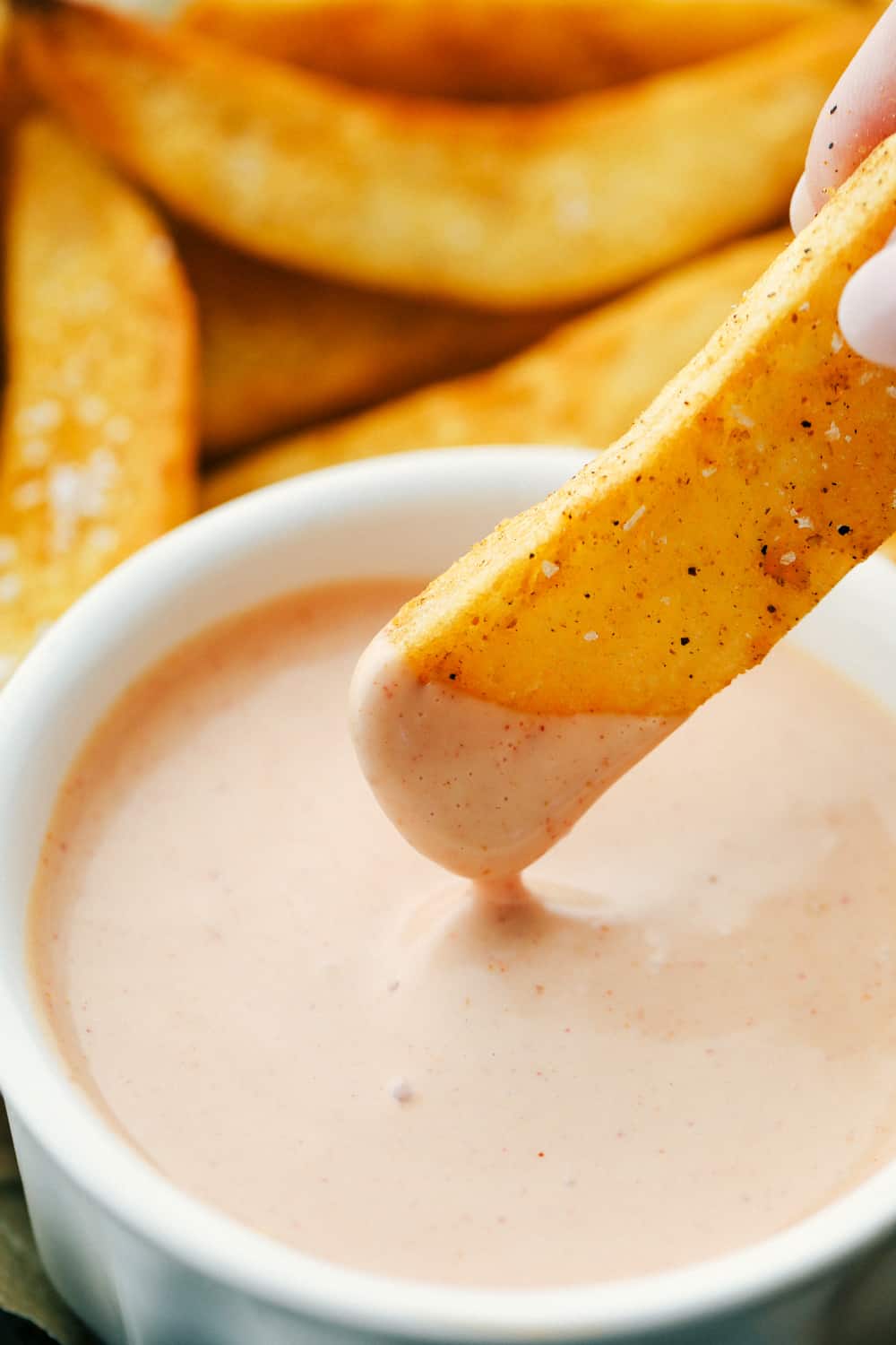 Fry being dipped in fry sauce dipping sauce. 