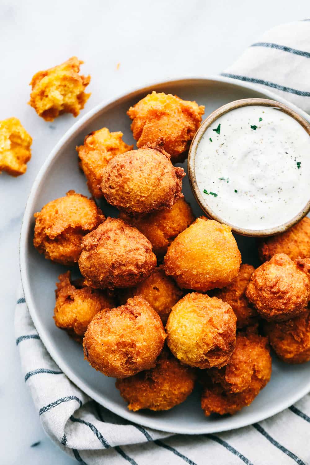 Hush Puppies on a plate with a side of tartar sauce. 