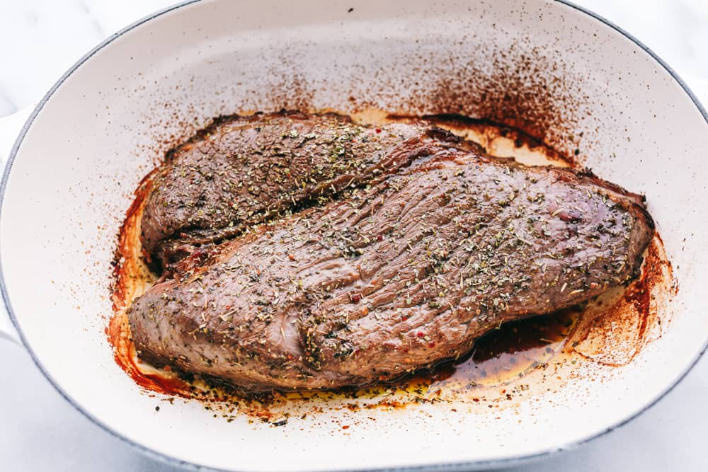 London Broil broiled and placed on a plate resting before slicing it. 