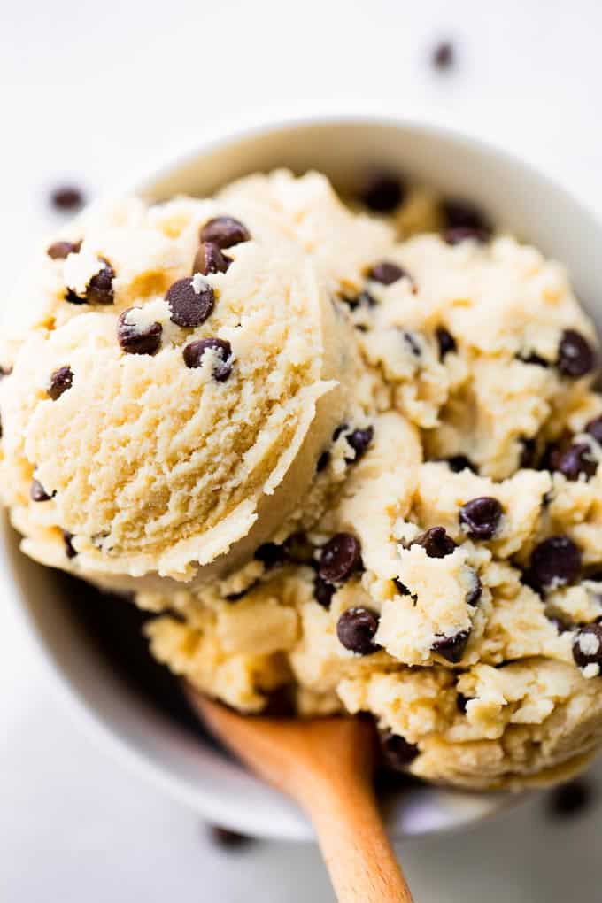 Edible cookie dough in a white bowl with a wooden spoon.