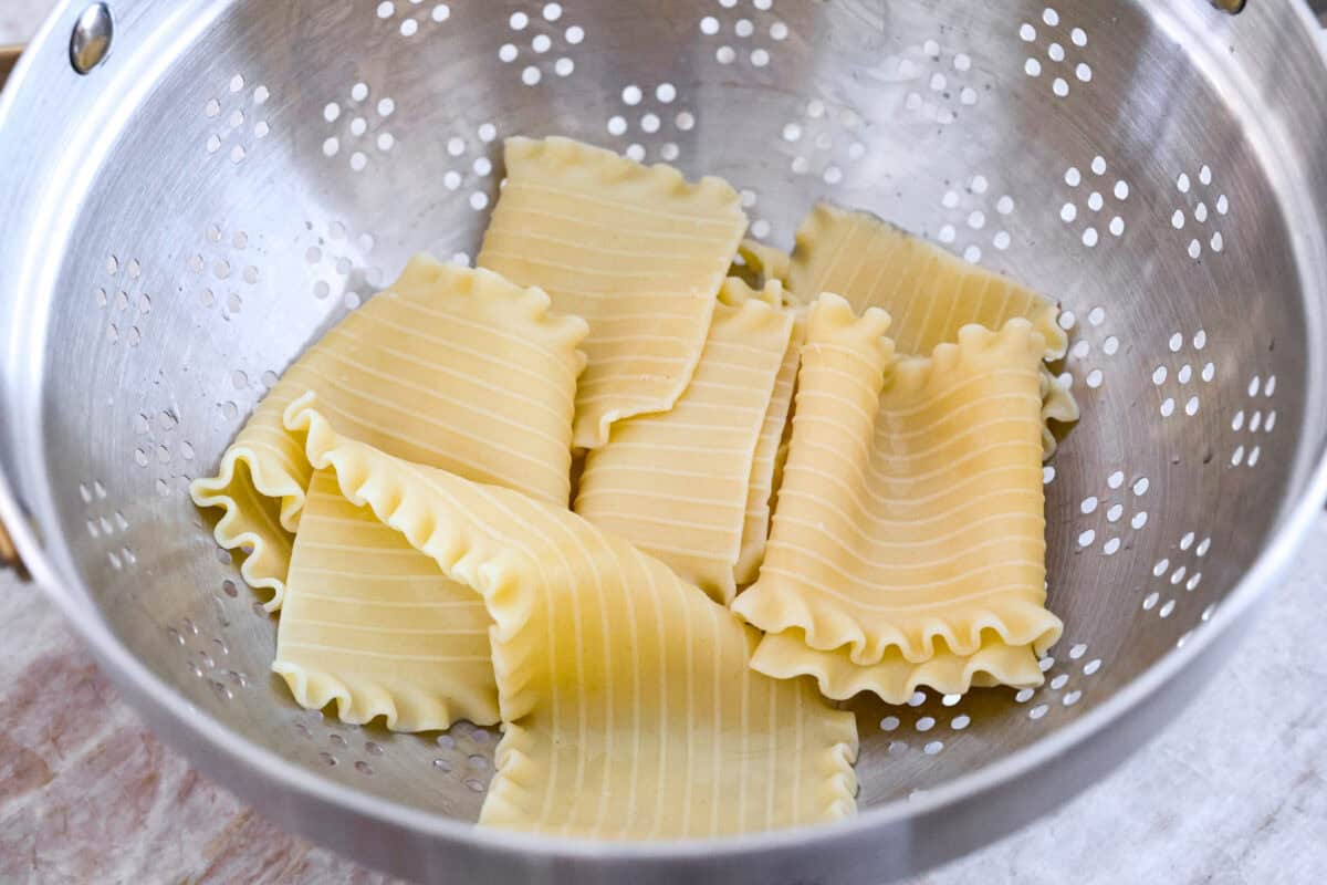 Overhead shot of cooked lasagna noodles in colander. 