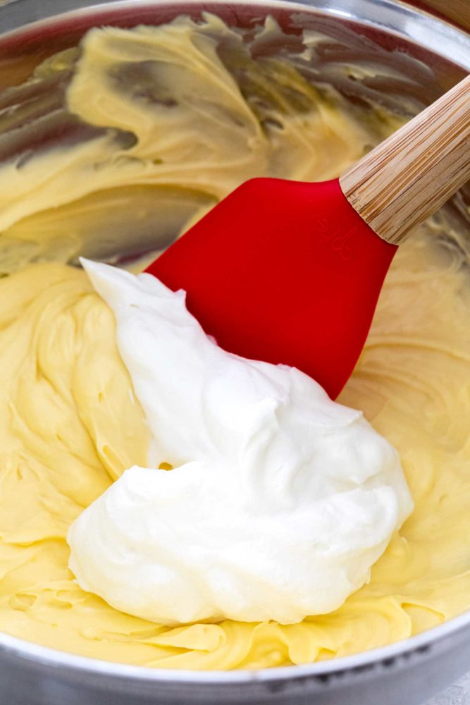 Spatula mixing eggs with cream in a bowl