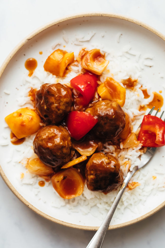 Sweet and sour meatballs served on top of rice in a plate