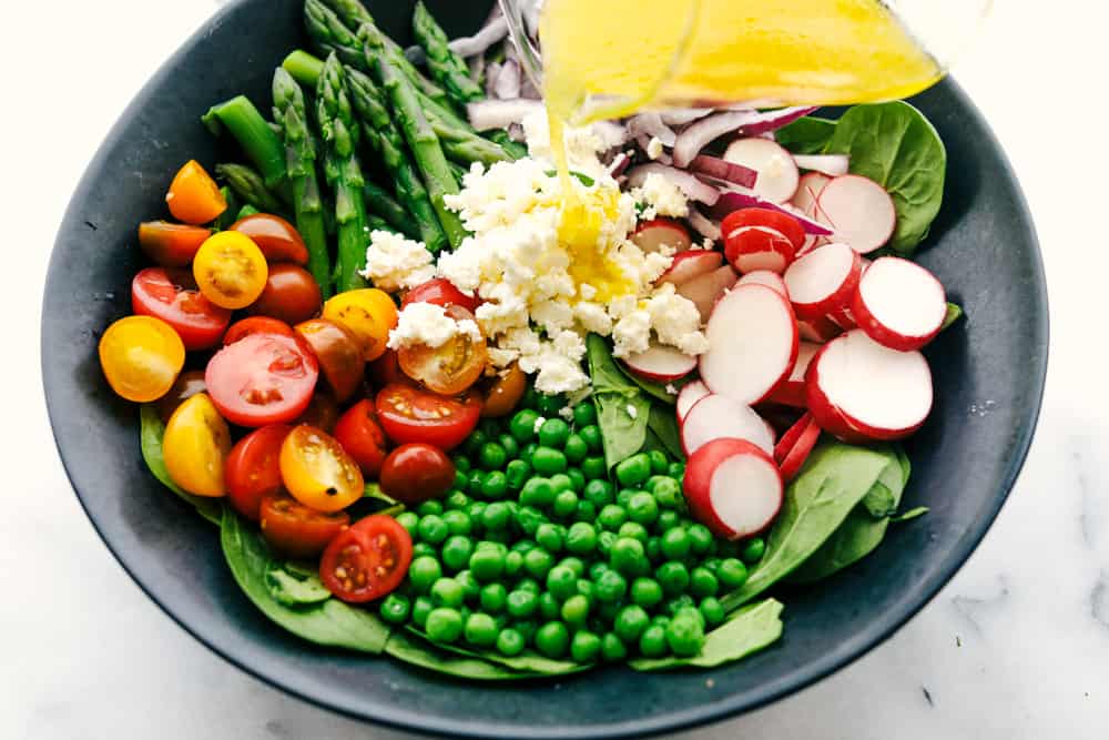 All the ingredients separated in a bowl with the lemon vinaigrette being poured over top.