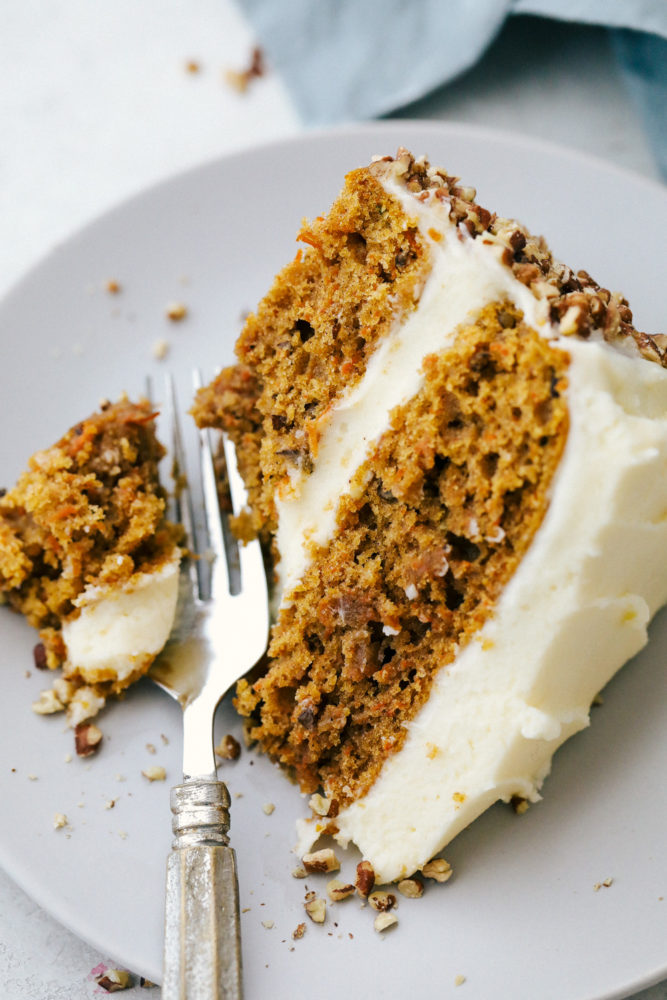 Carrot cake on a plate with a fork cutting off a bite. 