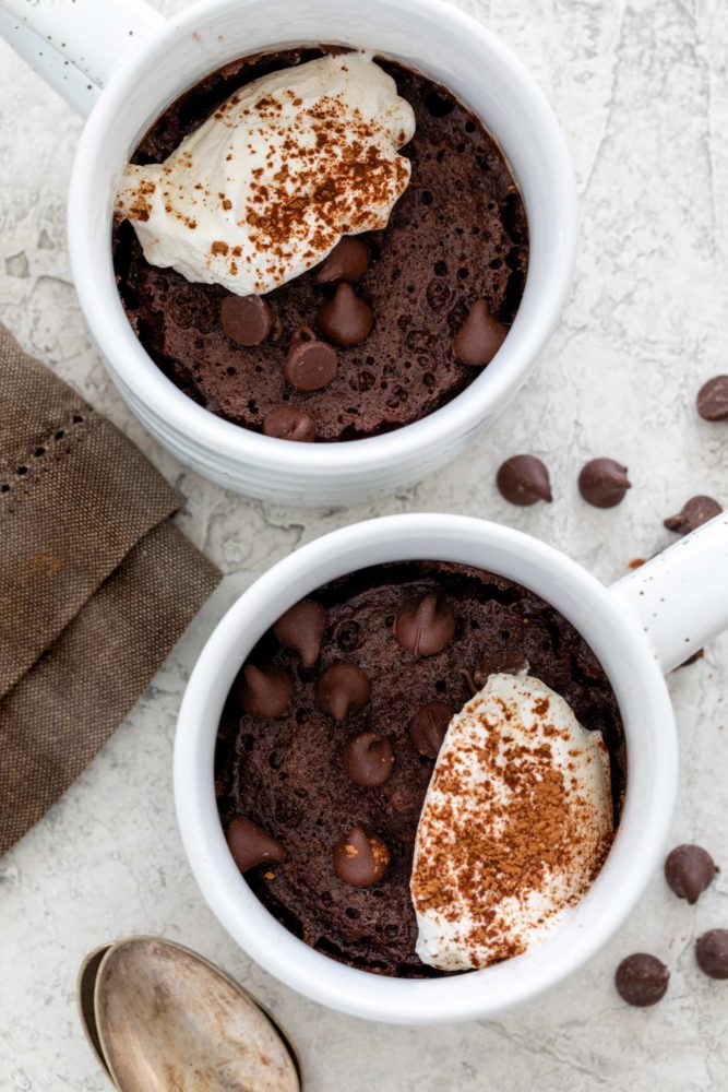 Two chocolate mug cakes topped with frosting