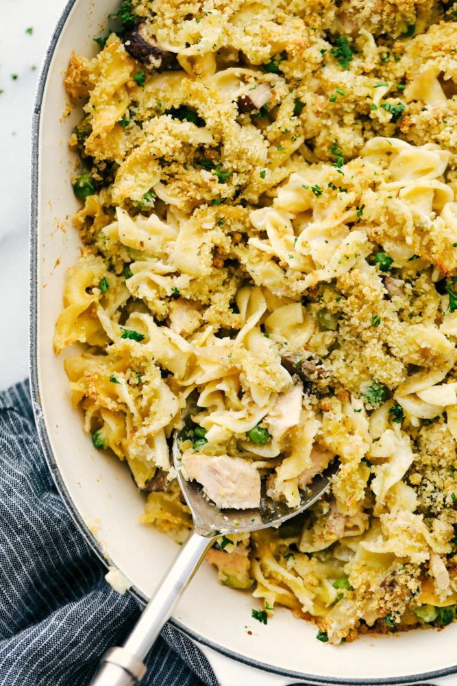 Tuna casserole in a casserole dish with a spoon in them. 