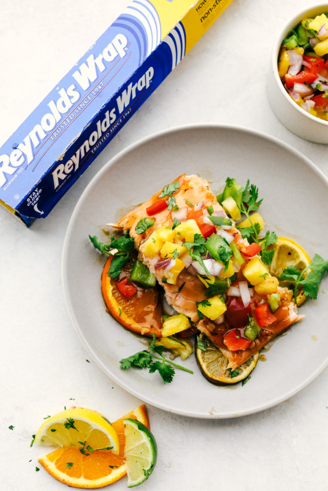 Overhead photo of the grilled citrus salmon filet with pineapple salsa on top with the Reynolds wrap box in the upper lefthand side. 