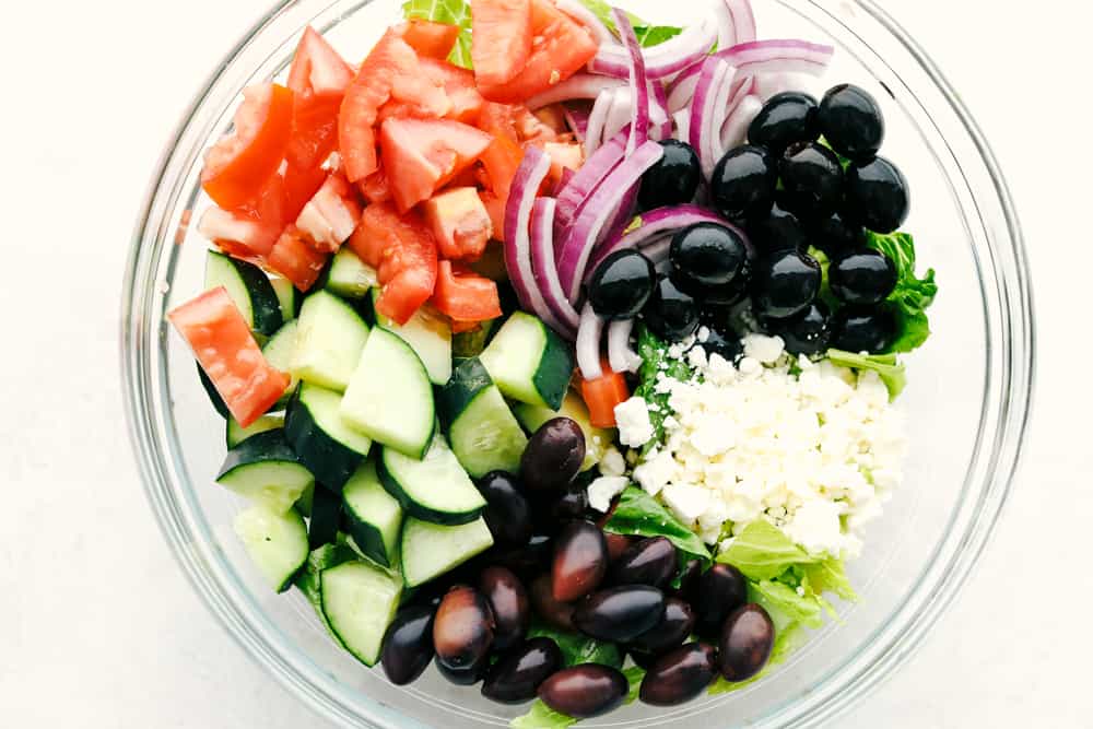 Greek Salad ingredients in a clear bowl.