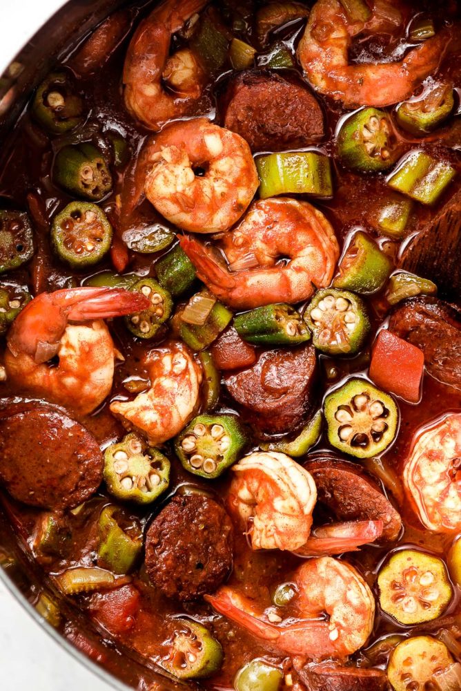 A stew of shrimp, okra, tomatoes, and sausage in a pot.