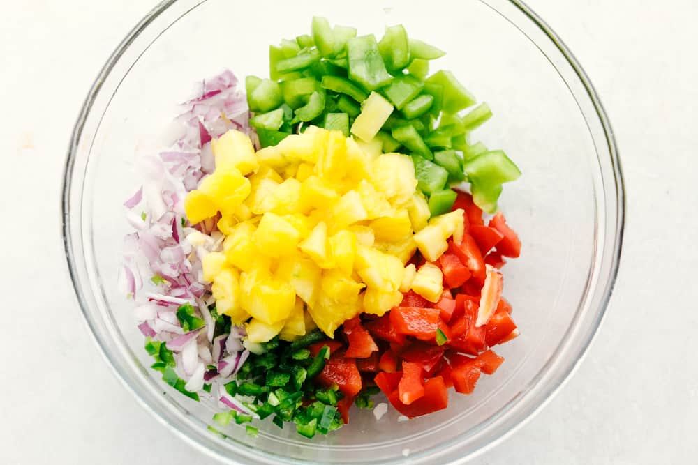 Ingredients for pineapple salsa in a clear bowl.