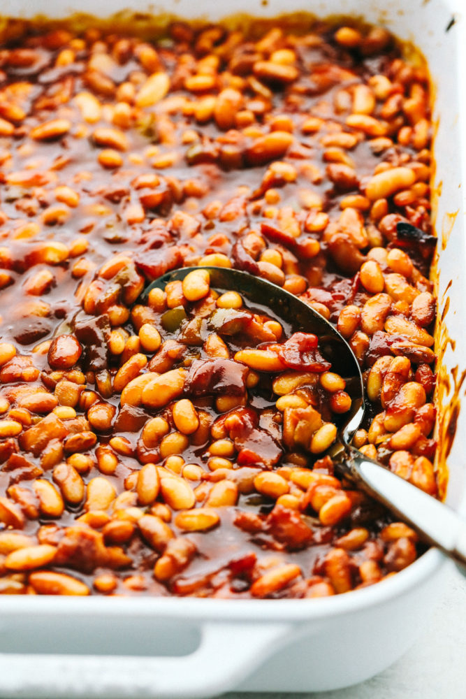 Scooping up baked beans with a serving spoon.