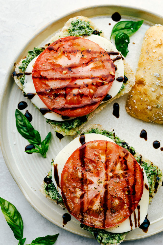 Balsamic glaze drizzled over caprese sandwiches on a plate.