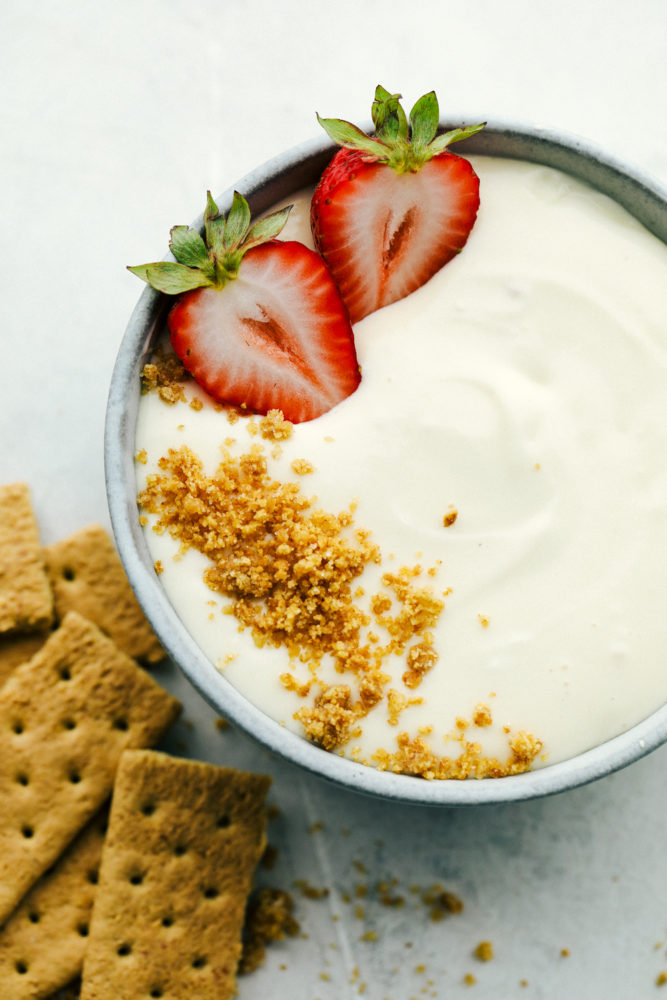 Graham cracker crumbles and strawberries garnishing cheesecake dip.