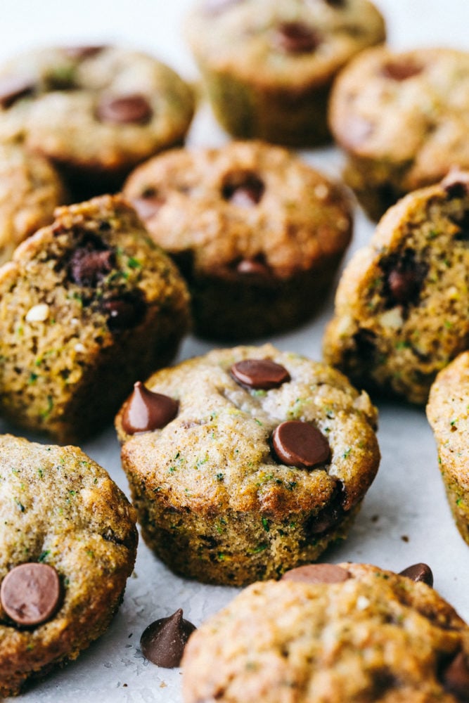 Scattered chocolate chip zucchini muffins sitting on parchment paper. 