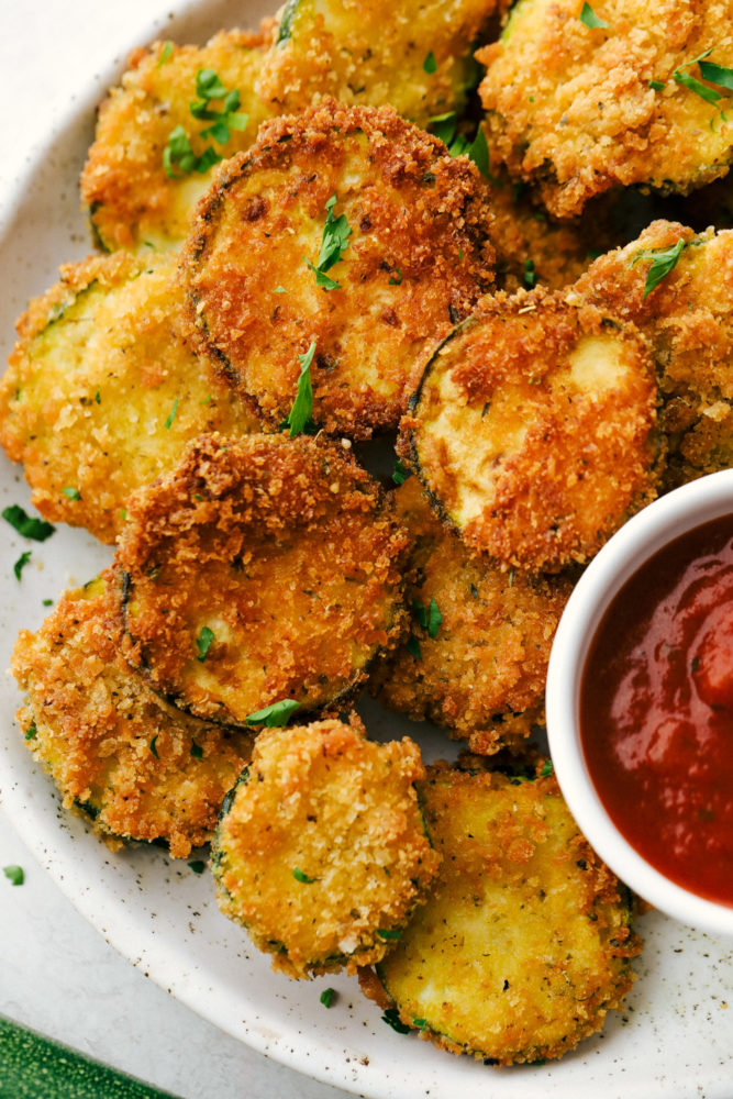 Crispy Parmesan Fried Zucchini on a white plate with marinara sauce.