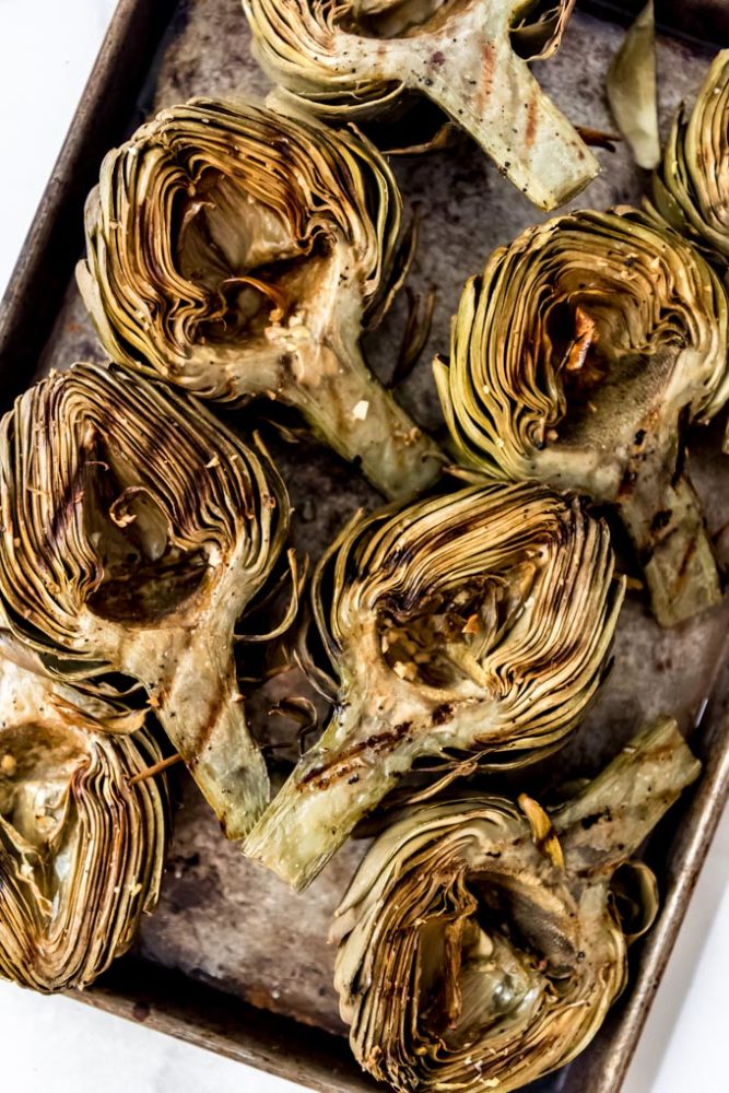 Grilled artichokes on a baking sheet.