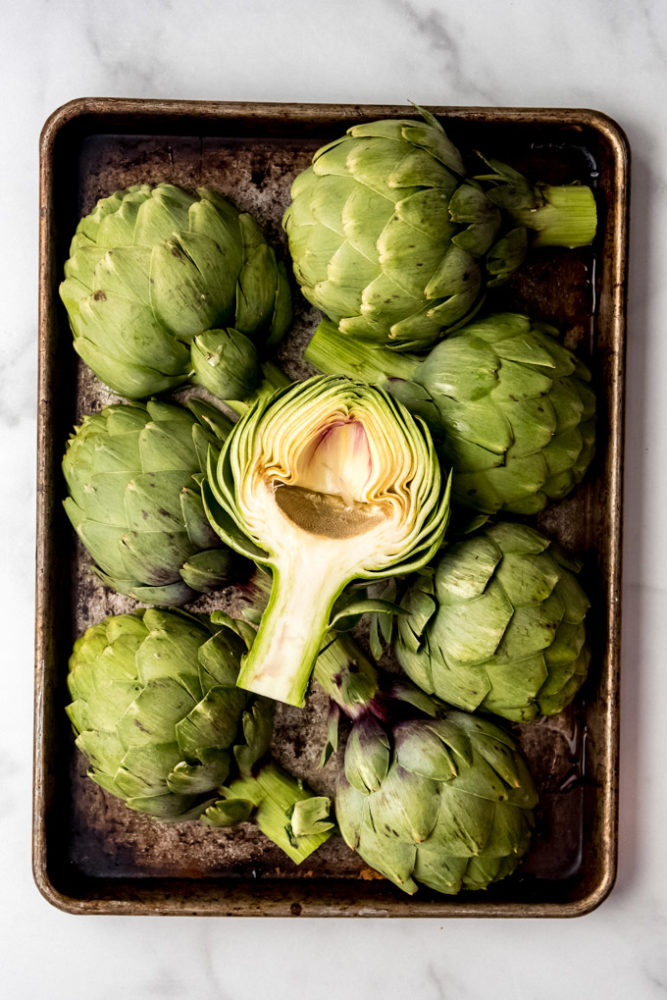 Artichoke halves on a baking sheet.