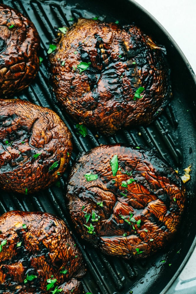 Portobello mushrooms cooking on a grill pan.