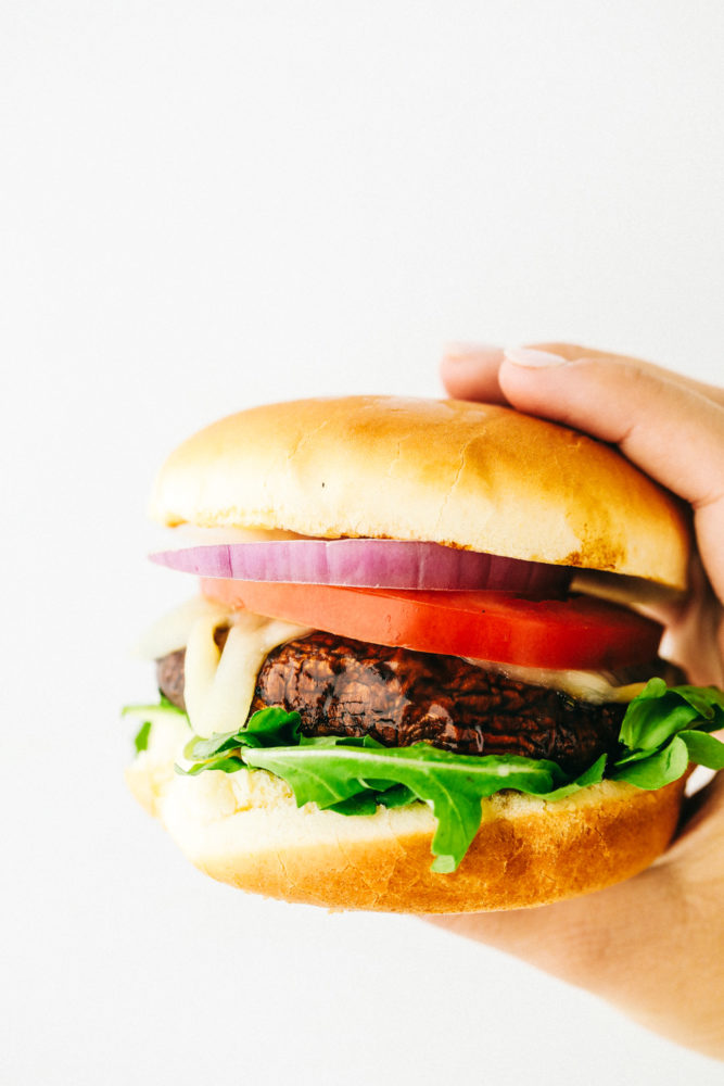 A hand holding a finished portobello burger.