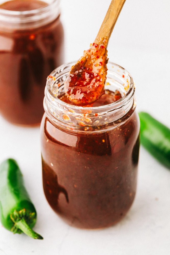 Dipping jalapeño jelly out of a glass mason jar.