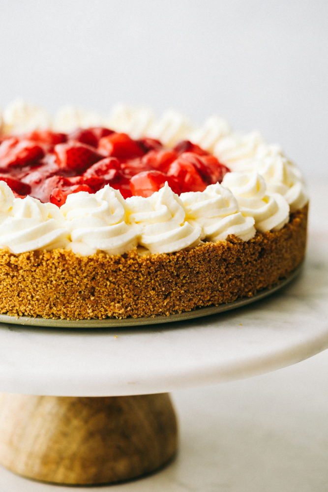 Close up on finished no bake cheesecake decorated with whipped cream and strawberries.