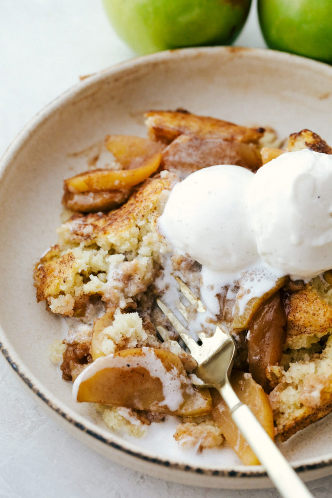 Apple cobbler on a plate topped with vanilla ice cream.