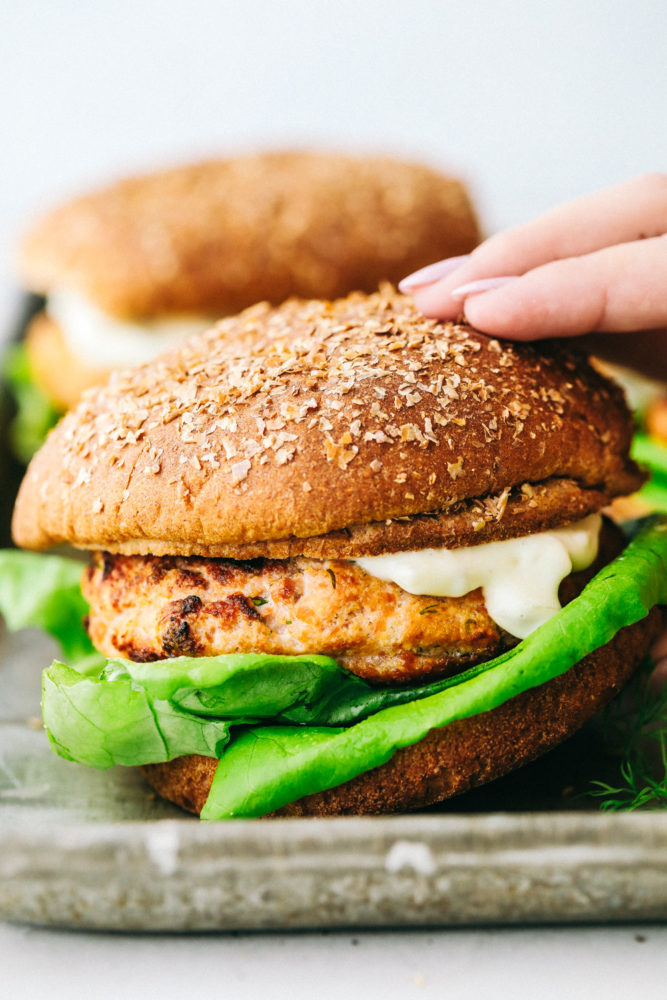 Close up on picking up a finished salmon burger.