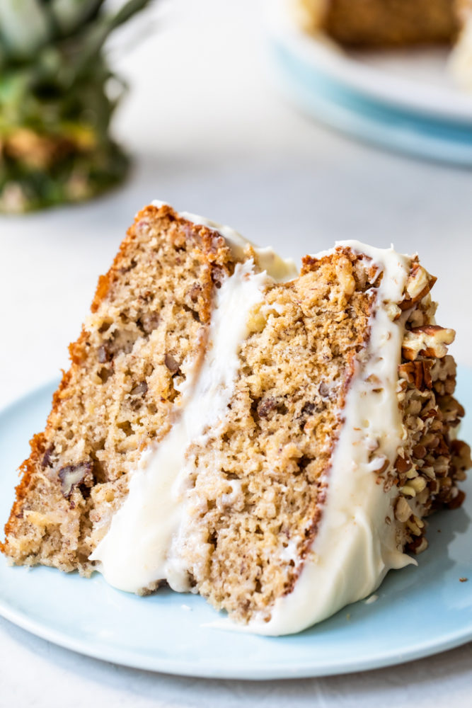 A slice of hummingbird cake laying on its side on a blue plate. 