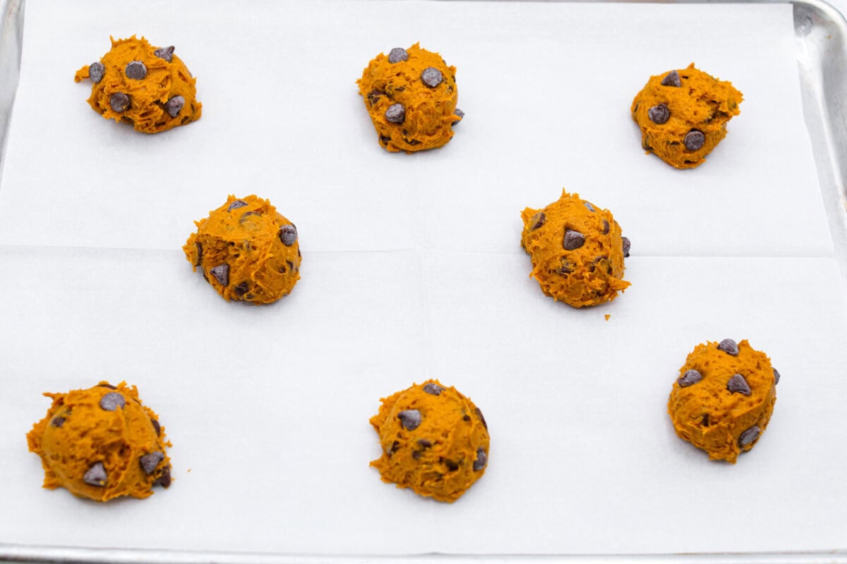 Overhead shot of scooped pumpkin chocolate chip cookie dough balls on a baking sheet. 