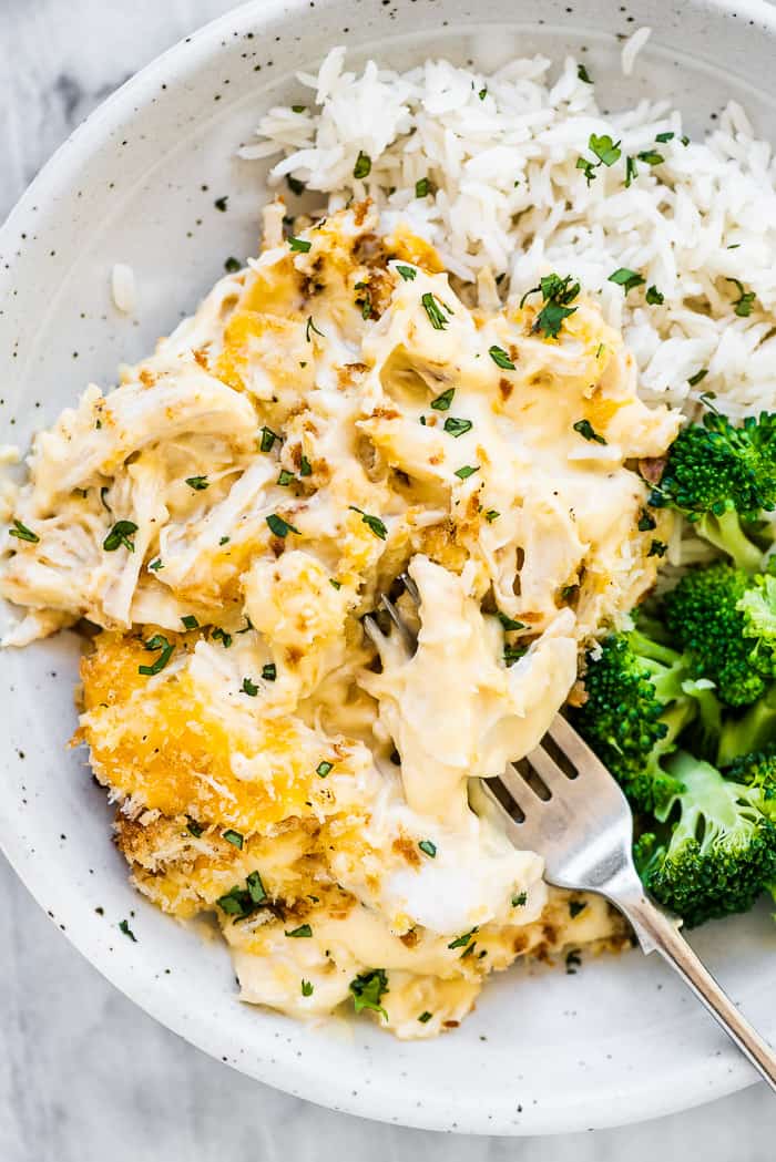 Chicken divan in a white bowl with broccoli and rice. 