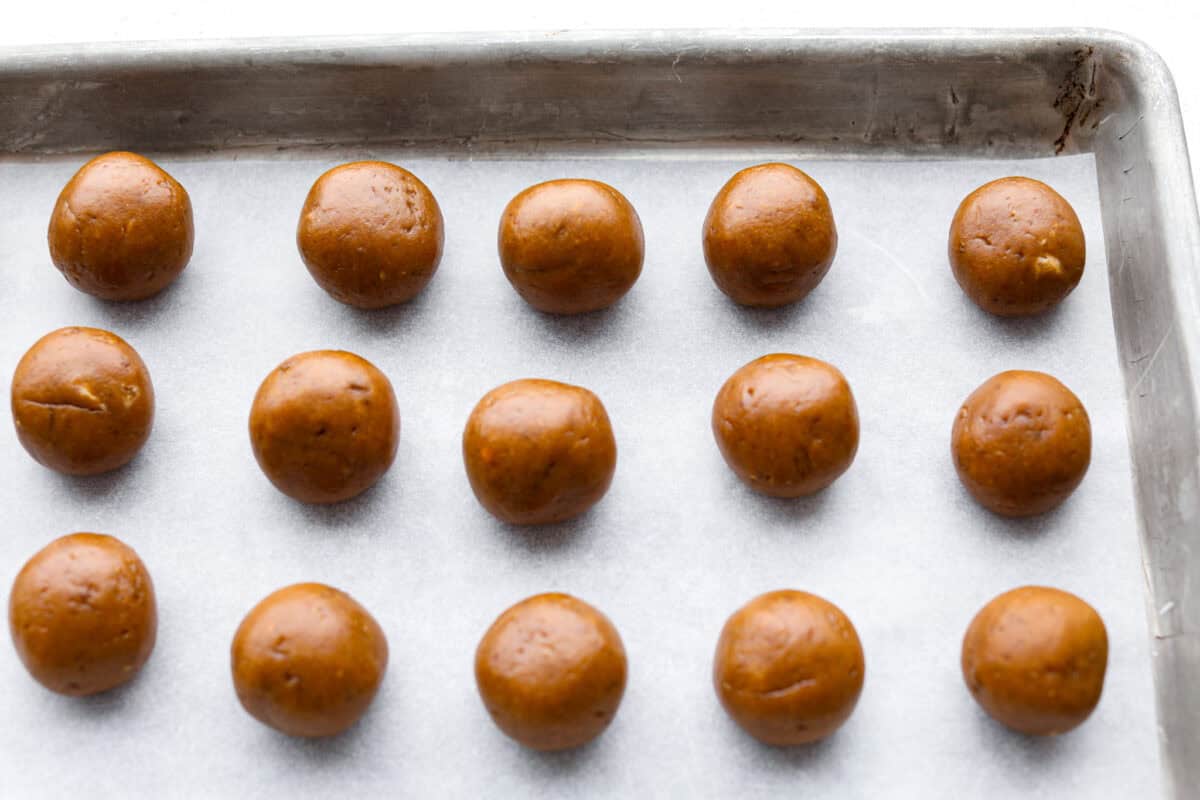 Overhead shot of rolled out truffle balls on parchment paper on a cookie sheet. 