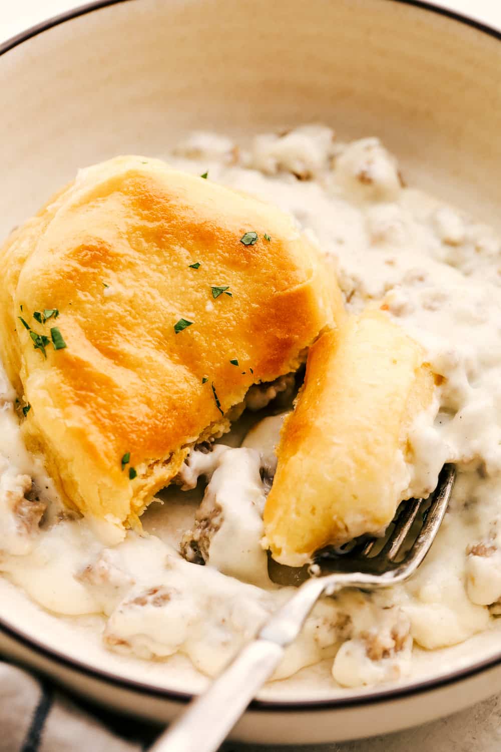 Golden flakey biscuits with savory rich sausage gravy on a plate.