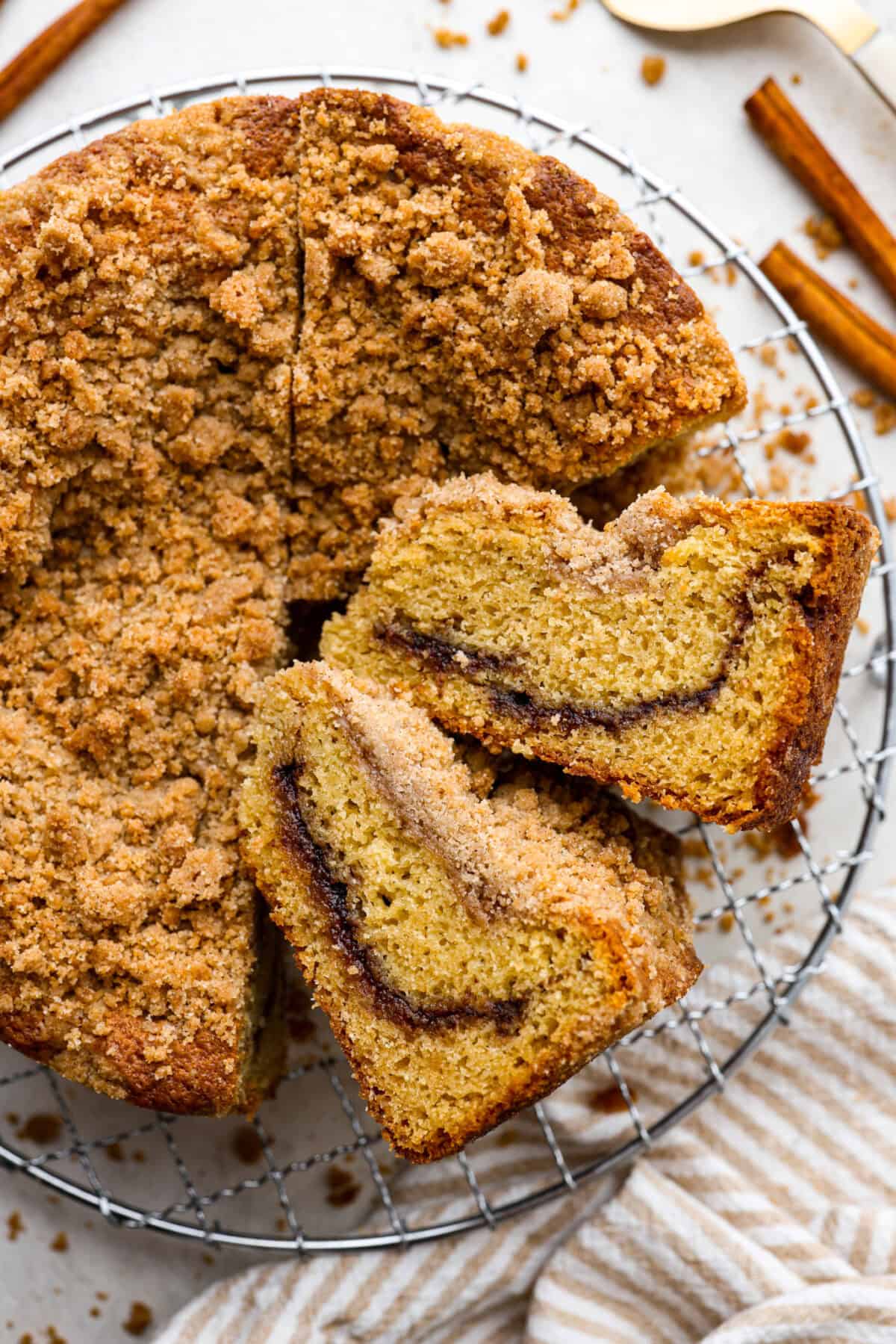 Overhead shot of completed cinnamon coffee cake with two slices on their side, all on a wire cooling rack. 