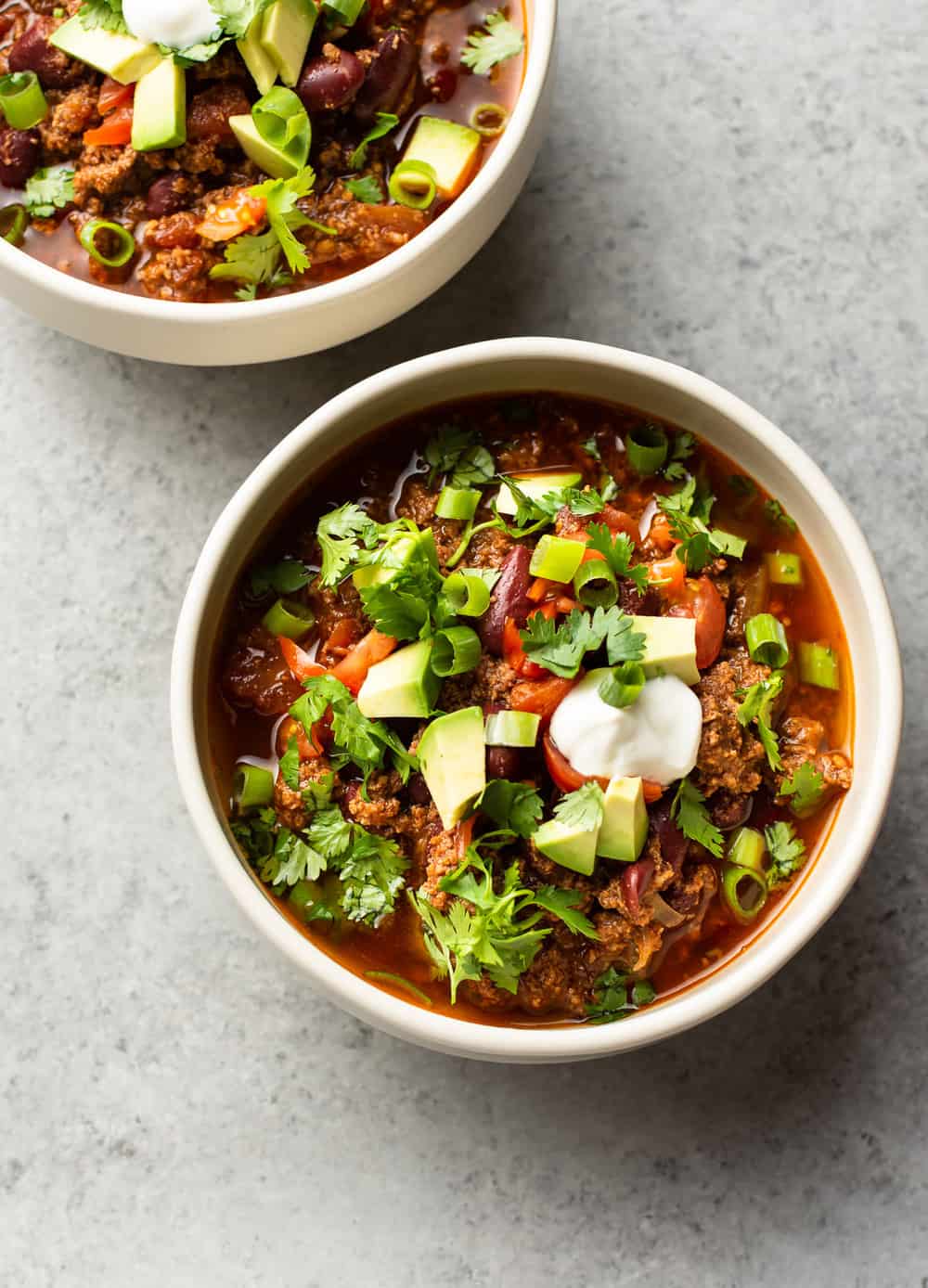 Individual servings in small bowls, topped with avocado, sour cream, cilantro and green onions. 