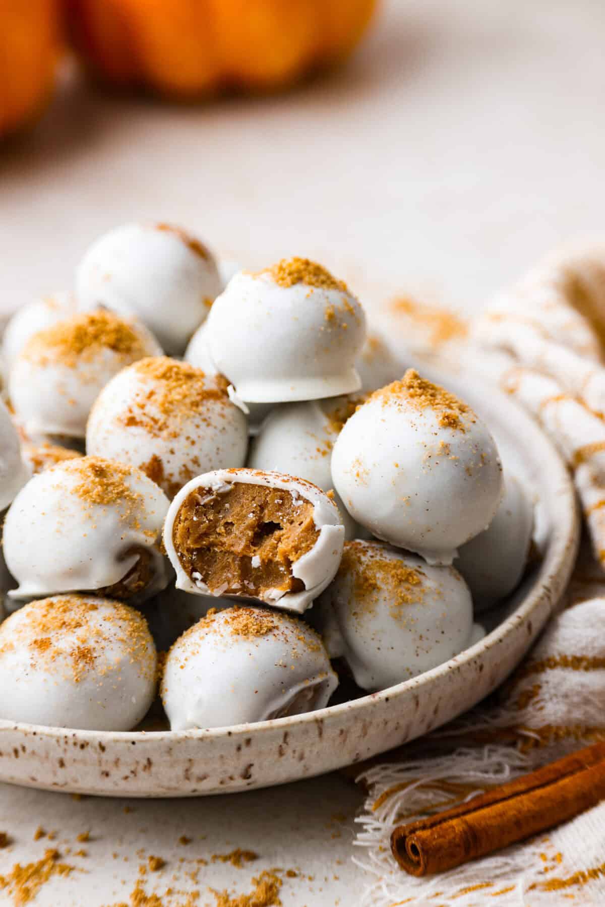 Side shot of a pile of pumpkin cream cheese truffles on a plate. 