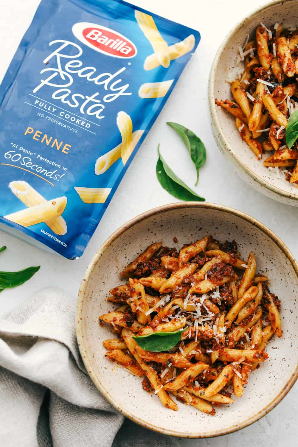 Sun dried tomato pesto pasta in a bowl with the barilla ready pasta on the side in the bag. 