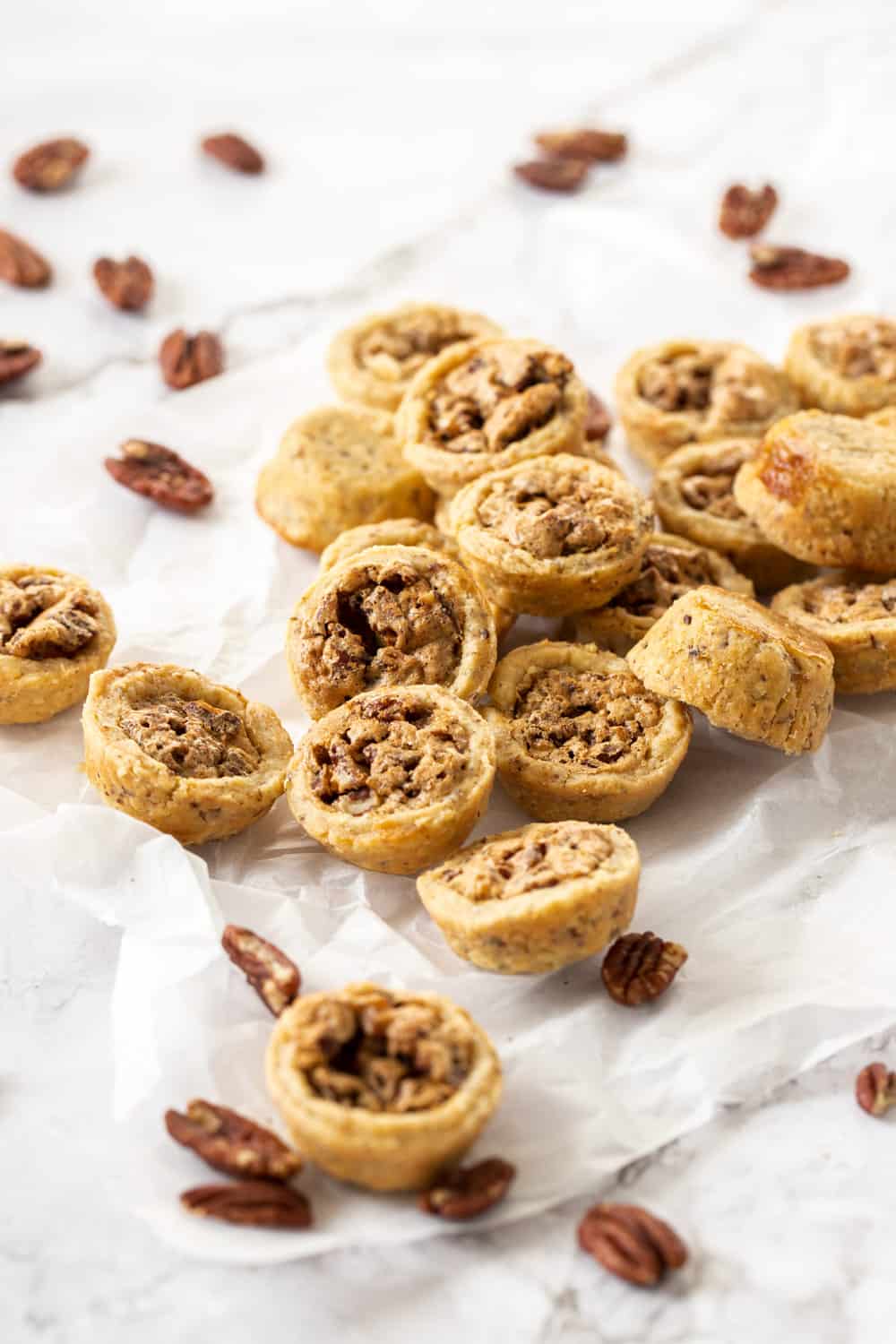 A pile of pecan tassies on a sheet of baking paper