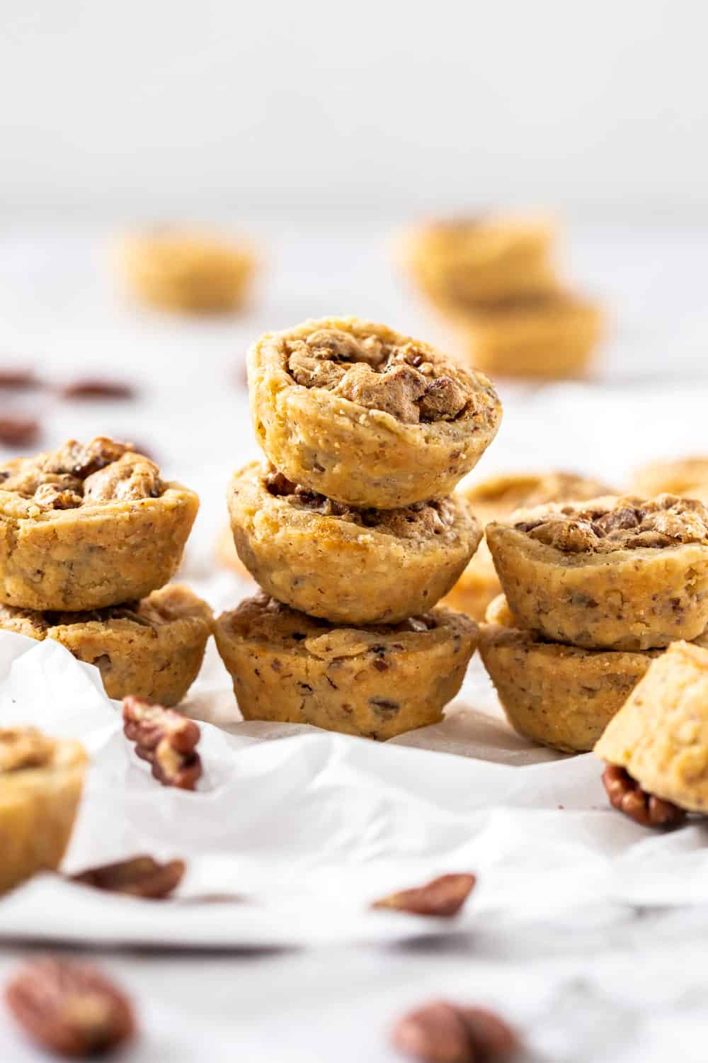 Small stacks of pecan tassies on a sheet of baking paper