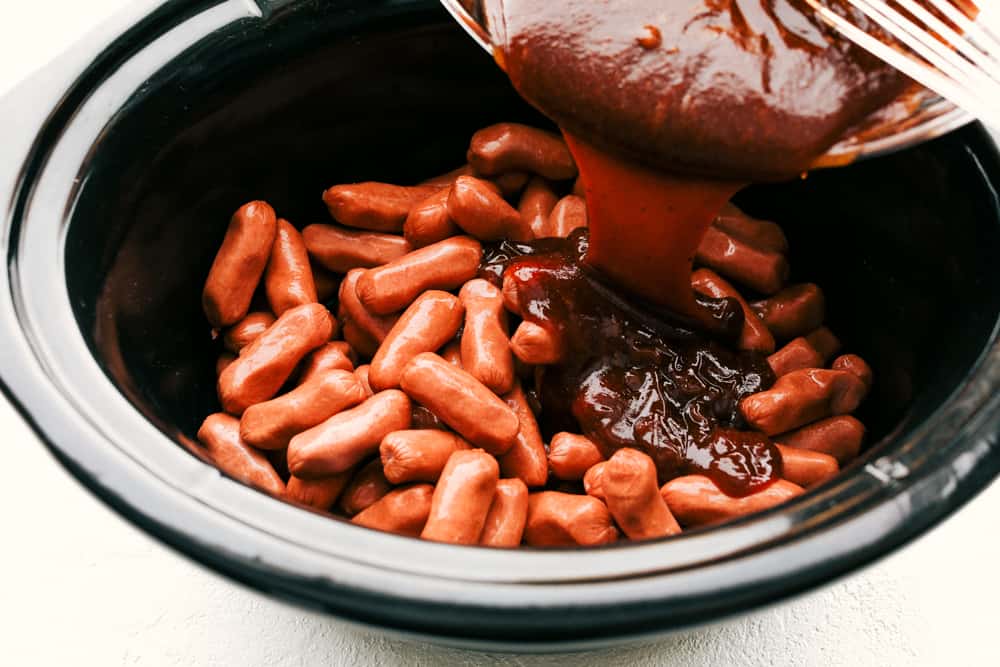 Sauce being poured over little smokies in the slow cooker.