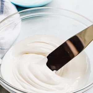 Royal icing in a glass bowl with a spreader.